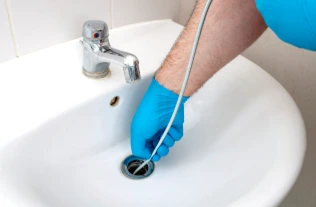 Drain cleaning with a cable tool in bathroom sink by plumber