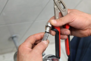 plumber connecting flexible water supply line with wrench